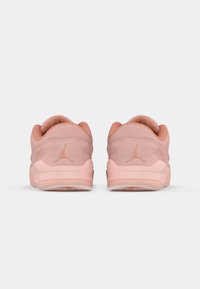 Rosa ruskind sneakers med en glat overflade, der har en polstret hæl og et diskret logo på bagsiden og siderne, minimalistisk design.