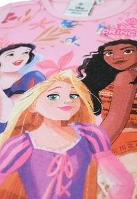 T-shirt en coton rose avec des motifs des princesses Disney, représentant Raiponce, Blanche-Neige et Vaiana avec des couleurs vives et des détails élaborés.