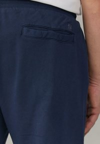 Navyblauwe katoenen broek met een gladde textuur, voorzien van een achterzak en een geribbelde tailleband voor comfort.