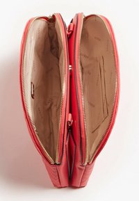 Portafoglio rosso a doppia zip aperto per mostrare due scomparti beige principali con tasche interne e rivestimento con logo "GUESS".