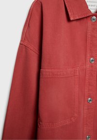 Camicia overshirt in denim rosso con colletto strutturato, tasca frontale, bottoni a pressione silver e finitura in tessuto testurizzato.