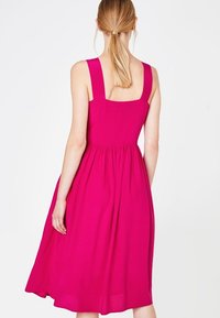 Vestido magenta sin mangas con escote cuadrado, cintura fruncida y falda en línea A, confeccionado en una tela suave y liviana.