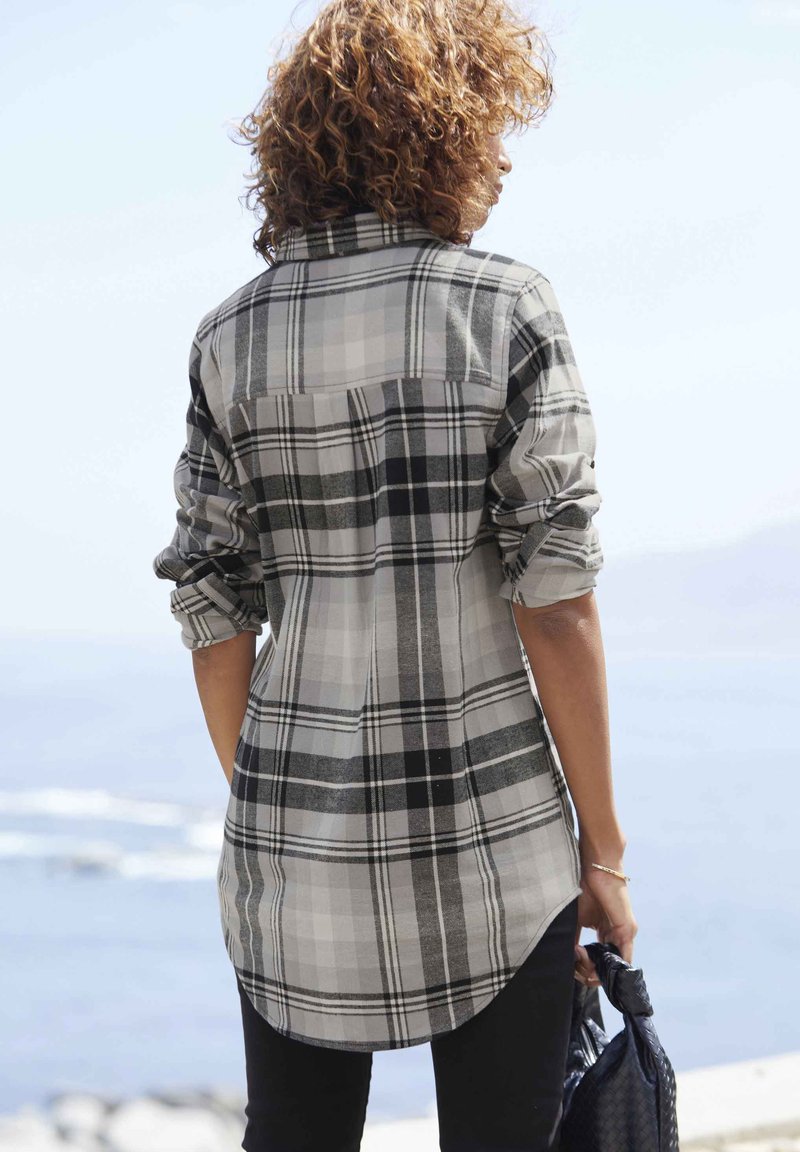 Camicia a scacchi grigia e bianca con maniche arrotolate, orlo curvo e dettaglio del giromanica sul retro, realizzata in tessuto leggero.