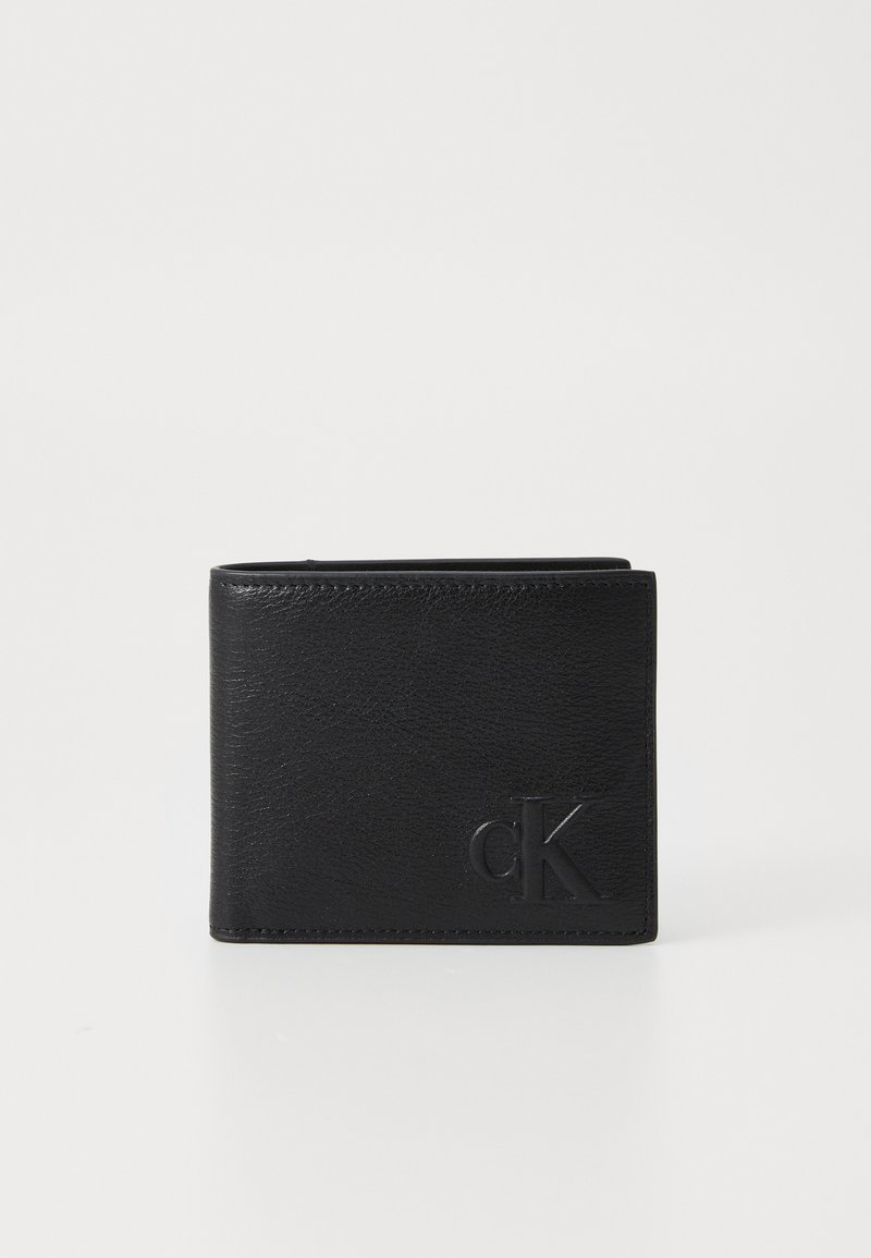 Portefeuille en cuir noir avec une finition texturée, design bi-fold et logo "ck" gaufré à l'avant. Style minimaliste sans embellissements supplémentaires.