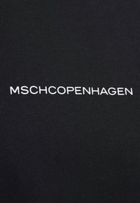 Black textured fabric featuring white embroidered text "MSCHCOPENHAGEN." The design is minimalistic with a smooth finish and no additional patterns.
