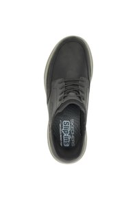 Sneaker nera con tomaia in pelle liscia, design con lacci, colletto imbottito e suola in gomma grigia. Soletta con la scritta "Skechers Slip-Ins."