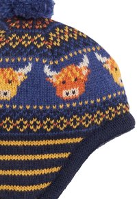 Il berretto a maglia presenta un motivo blu e giallo con motivi di mucche Highland, una base a righe blu scuro e un pompon blu sulla cima.