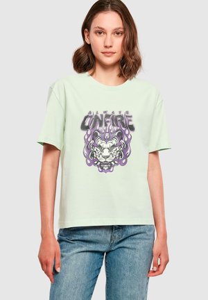 Mintgrünes Baumwoll-T-Shirt mit kurzen Ärmeln, das einen grafischen Druck von einem Bärenkopf mit lila Flammen und dem Text "ALWAYS ON FIRE" zeigt.