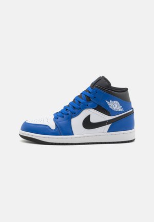 Baskets montantes avec des panneaux en cuir bleu, blanc et noir. Dotées d'un embout perforé, de lacets plats et du logo emblématique de Nike en forme de virgule.