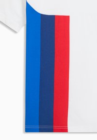 Λευκό ύφασμα με τρεις κατακόρυφες ρίγες σε μπλε, ναυτικό μπλε και κόκκινο, που διατρέχουν την αριστερή πλευρά του υφάσματος.