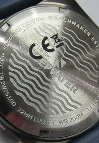 Zapięcie zegarka ze stali nierdzewnej z wygrawerowanym tekstem, falistymi liniami i oznaczeniem "TIMEX" oraz "WATER RESISTANT 200M."