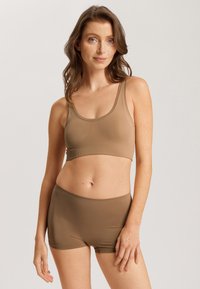 Conjunto de sujetador deportivo y pantalones cortos de tiro bajo en marrón, con una textura suave, tirantes anchos y una cintura elástica para un ajuste cómodo.