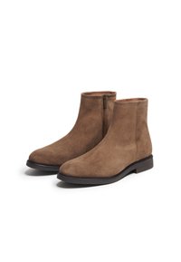 Bottines en daim marron avec une texture lisse, bout rond et détail de fermeture éclair sur le côté. Semelle noire robuste avec un léger talon.