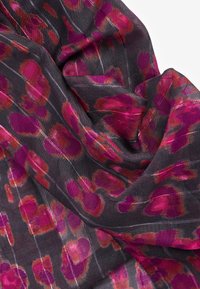 Écharpe transparente avec un fond noir présentant de grands motifs floraux roses et rouges. Texture légère avec des rayures horizontales subtiles.