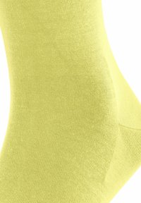 Helle gelbe Baumwollsocke mit glatter Textur, geripptem Muster und nahtlosem Zehendesign. Verfügt über einen crew-langen Schnitt.