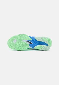 Suola di scarpa sportiva in gomma verde e blu, con motivi testurizzati e un design non marcante, dotata di elementi per una presa migliorata.