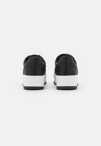Zwarte leren sneakers met een witte tussenzool en een zwarte rubberen buitenzool. Rond ontwerp met een gewatteerde kraag en minimalistische stikseldetails.