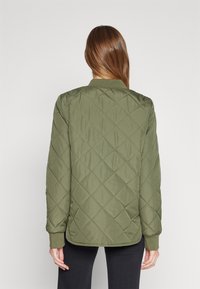 Quiltad grön bomberjacka med ribbat krage och ärmslut. Har diamantstiktning och en avslappnad passform, lämplig för avslappnad klädsel.
