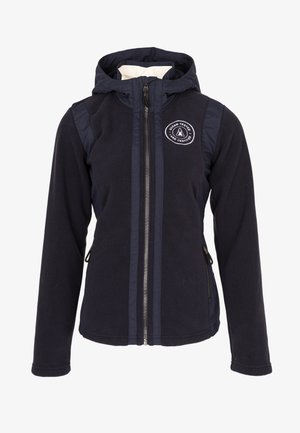 Chaqueta azul marino con capucha, cierre frontal, bolsillos laterales con cremallera y un parche redondo que dice "Ocean Tested Land Certified" en el pecho.