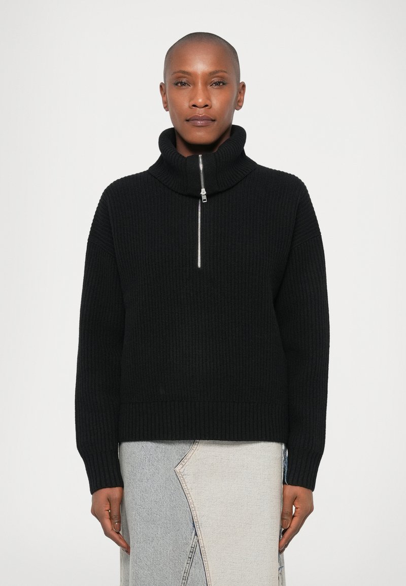 Musthave mustriba pruun kampsun kõrge kaelusega ja poolsiidiga kinni. Omab lõdva lõiget ja pikki varrukaid. Minimalistlik disain.