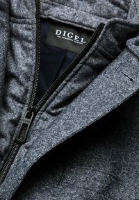 Gray textured jacket with a black zipper, featuring a label inside. The fabric has a subtle pattern and smooth inner lining.