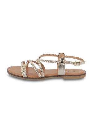 Sandalo piatto in argento metallico con cinturini intrecciati e una cinghia alla caviglia con fibbia, dotato di una suola beige e design minimale.