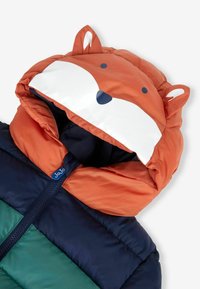 Padded bunda s kapucňou v tvare oranžovej líšky, so svetlými akcentmi na tvári, modrým zipsom a farebne blokovaným telom v zelenej a námorníckej modrej farbe.