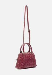 Czerwony torebka skórzana o pikowanym wzorze z dwoma uchwytami i odczepianym paskiem na ramię. Posiada geometryczną teksturę i zamek błyskawiczny na górze.