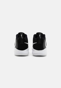 Scarpe sportive nere con accenti bianchi, dotate di una tomaia testurizzata, colletto imbottito e suola in gomma bianca. Logo Nike evidente sul tallone.