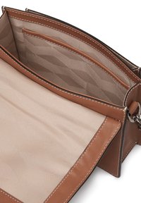 Brun läderhandväska med ett inre som har en texturerad beige foder, flera fickor och kontrasterande vit sömnad.