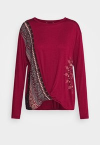 Burgunderfarbendes Langarmshirt mit einem geknoteten Vorderteil und einem gemusterten Seitenpaneel in Schwarz-, Creme- und Brauntönen. Weiches Stoffgefühl.