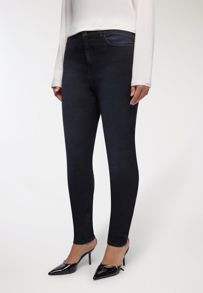 Jasno niebieskie dżinsy slim fit w ciemnym odcieniu, o gładkiej fakturze, pięciopakowym wzornictwie i średnim stanem. Połączone z czarnymi lakierowanymi szpilkami.