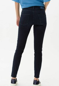 Skinny jeans in donker denim, met een middelhoge taille, achterzakken en een slanke pasvorm tot aan de enkel. Textured blauwe trui erboven.