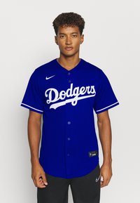 Dodgers beisbolo marškiniai karališkos mėlynos spalvos, su baltais užrašais ir juostelėmis, trumpomis rankovėmis, mygtukų priekyje ir etikete apačioje.