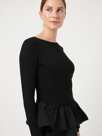 Sort langærmet top med ribbet krop og flæseprydet peplumkant, lavet af et let materiale med en glat tekstur.