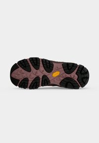 Semelle d'une chaussure de randonnée avec des crampons noirs profonds sur une base marron et un petit logo Vibram jaune près du centre.