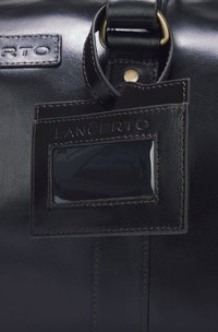 Czarna skórzana zawieszka do torby o gładkiej fakturze, z wytłoczonym napisem "LANCERTO" i przezroczystym okienkiem na identyfikację. Widoczne elementy w złotym kolorze.