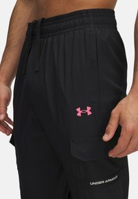 Zwarte sportshorts met een elastische tailleband en verstelbaar trekkoord. Voorzien van een roze logo en cargozakken voor opbergruimte. Ademend materiaal.