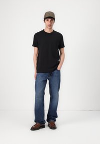 Must musta T-särk, sinised denim teksad plekkidega, pruun nahast king, ja ruudulise mustriga müts. Juhuslik, mugav lõige.