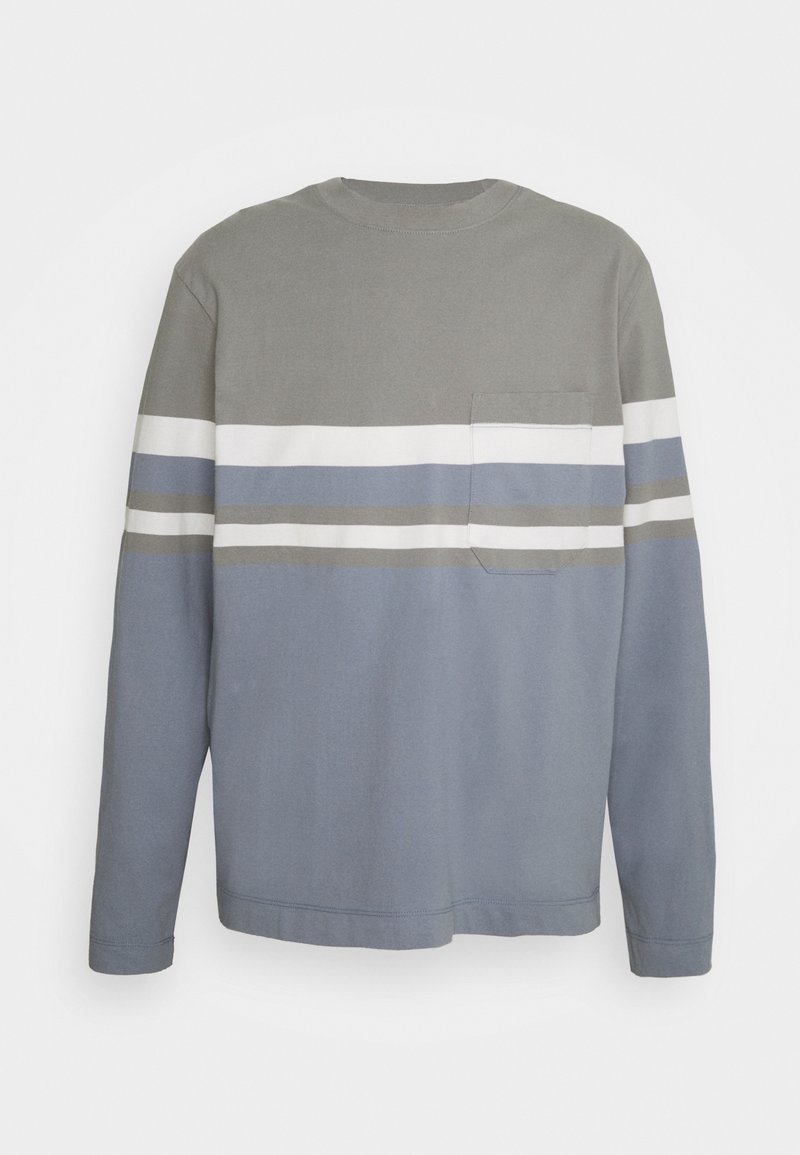 Maglietta a maniche lunghe con girocollo, caratterizzata da strisce orizzontali grigie, bianche, blu e taupe, e una tasca sul petto lato sinistro.