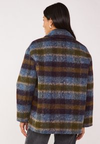 Giacca in misto lana con motivo a quadri blu, verde e viola, con una finitura strutturata e colletto a punte.