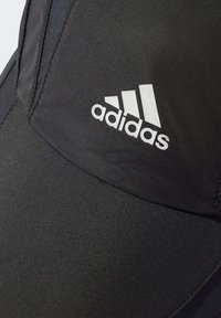 Crna sportska kapa od sintetičkog materijala s zakrivljenim vrhom i bijelim adidas logotipom sprijeda. Teksturirana površina s detaljima šavova.