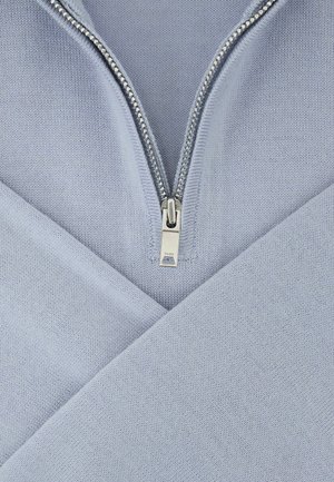 Light blue pullover with a zippered neck. Knit texture, angled design with overlapping sections, and a silver zipper detail.