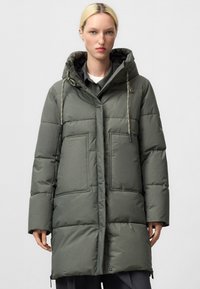 Giacca a vento verde con cappuccio, caratterizzata da un design trapuntato, due ampie tasche frontali e dettagli con cordino sul cappuccio. Texture liscia.