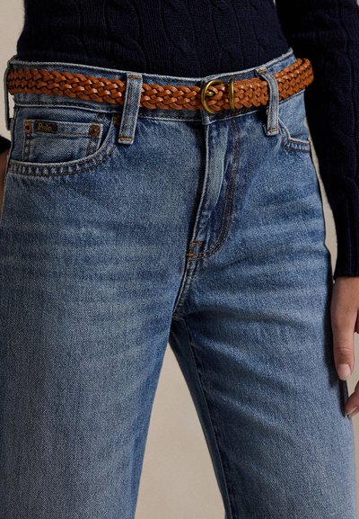 Μπλε τζιν από denim με καφέ πλεκτή δερμάτινη ζώνη και ορειχάλκινη αγκράφα, φορεμένο με σκούφο ριμπ μαύρο που φαίνεται στη μέση.