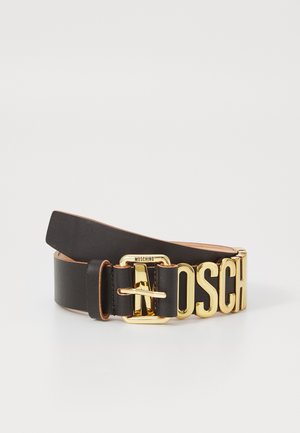 Melna ādas josta ar zelta metāla sprādzi un lielām zelta burtu norakstēm, kas veido vārdu "MOSCHINO" uz baltas fona.