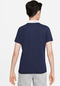 Marine blauwe polo met korte mouwen en een witte kraag. Glad materiaal, klassieke pasvorm, rechte onderkant en korte mouwen. Eenvoudig, strak design.