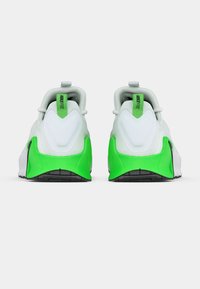 Nike Free sneakers, featuring a white upper, green accents, smooth texture, rounded shape, and black rubber sole with tread patterns.