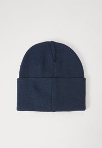 Căciulă tricotată bleu marin cu margine pliată, așezată pe un fundal neutru, deschis la culoare.