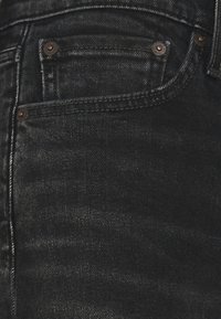 Svarta denimjeans med en texturerad yta, femficksdesign och bronserade nitar på framfickorna. Klassiker med rak benpassform.